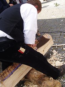 a german carpenter hand hewing a beam with a broadaxe